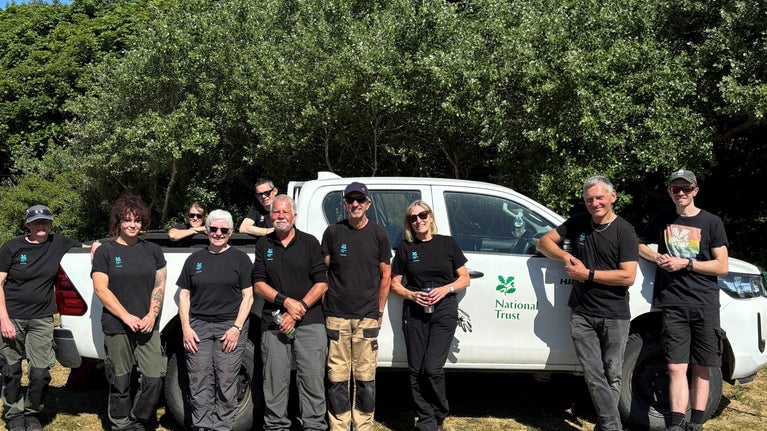 Volunteers and rangers looking happy, standing in front of a National Trust branded white van